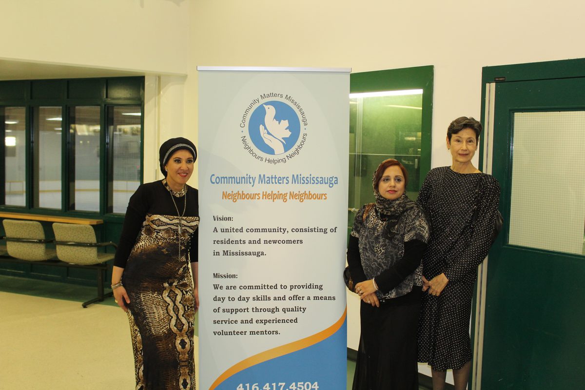 Community Matters Mississauga volunteers standing together beside the organization's banner